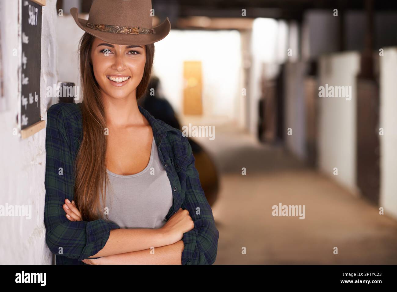 Roughing it at the ranch. An attractive young cowgirl standing in the stables Stock Photo