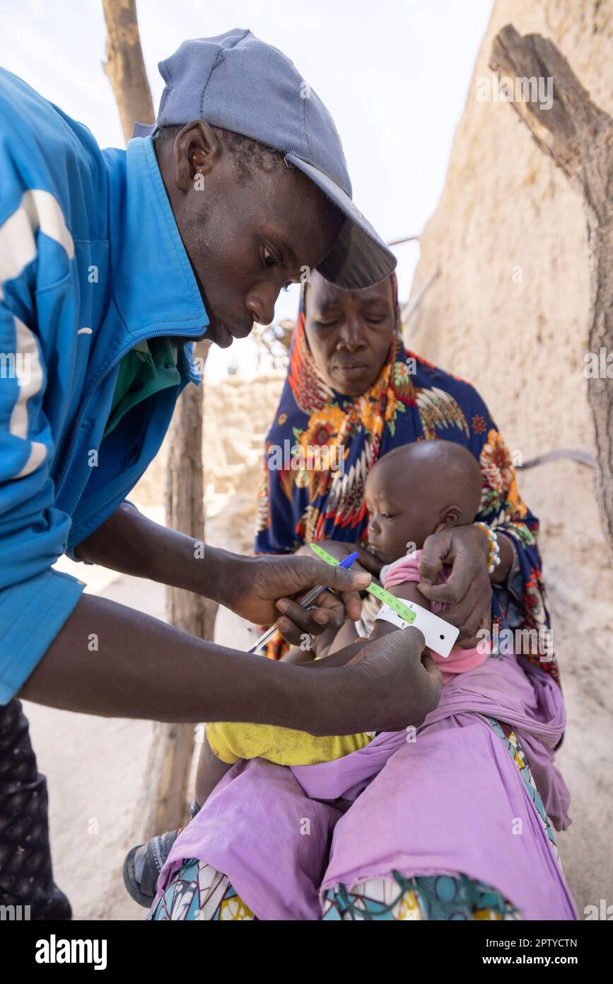 A health care worker measures the upper-arm circumference of a young child to measure nutrition levels in Segou Region, Mali, West Africa. 2022 Mali drought and hunger crisis. Stock Photo