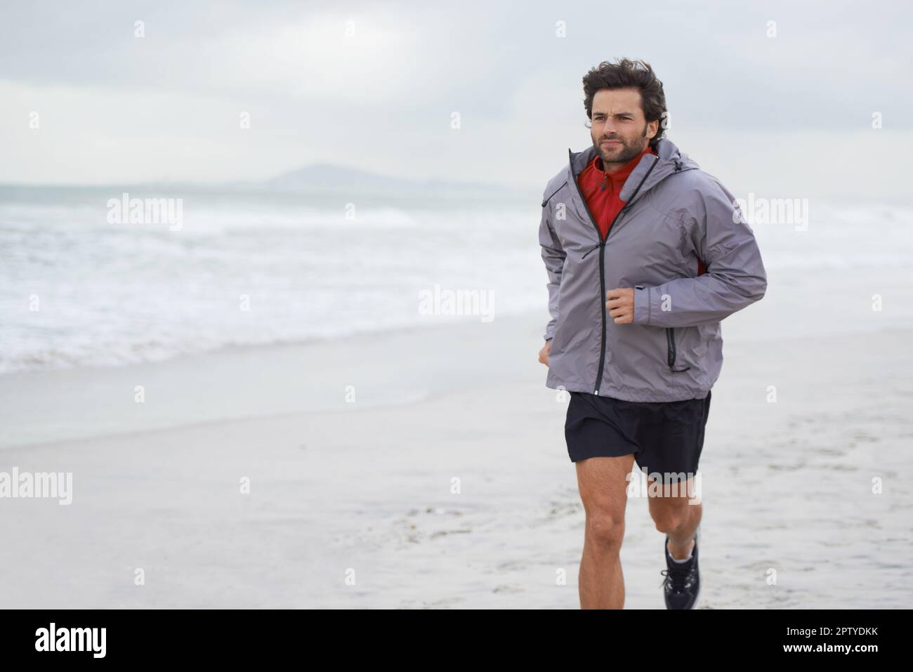 Taking a morning run on the beach. a handsome young man running on the