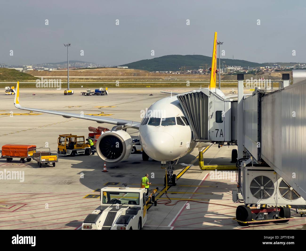 Istanbul, Turkey, 07.23.2022; Pegasus Airlines docket to jet bridge at Sabiha Gokcen Airport. Ground staff preparing for take off. Outdoors, sunny day Stock Photo