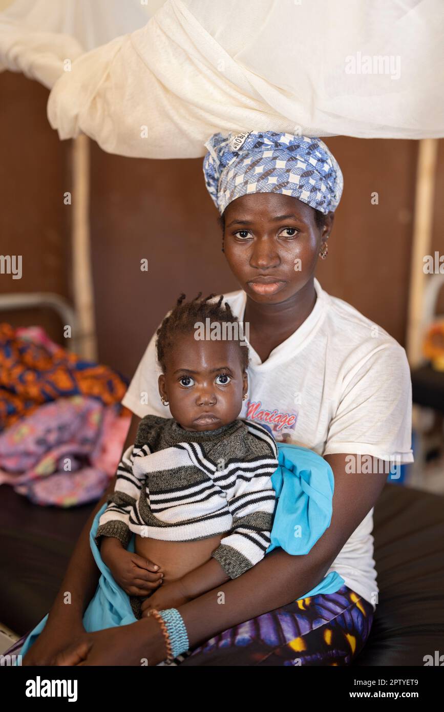 A mother sits in the malnutrition ward of a hospital with her young daughter in Segou Region, Mali, West Africa. 2022 Mali drought and hunger crisis. Stock Photo