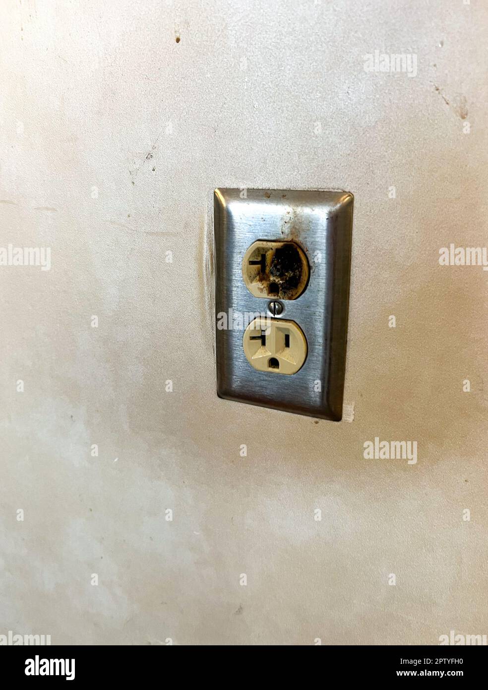 Damaged faulty electrical outlet on wall presented a hazard Stock Photo