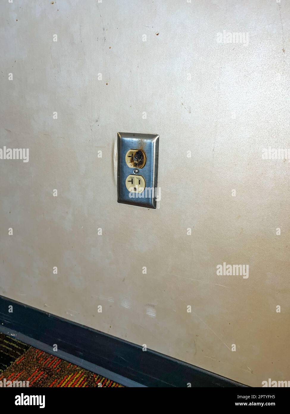 Damaged faulty electrical outlet on wall presented a hazard Stock Photo