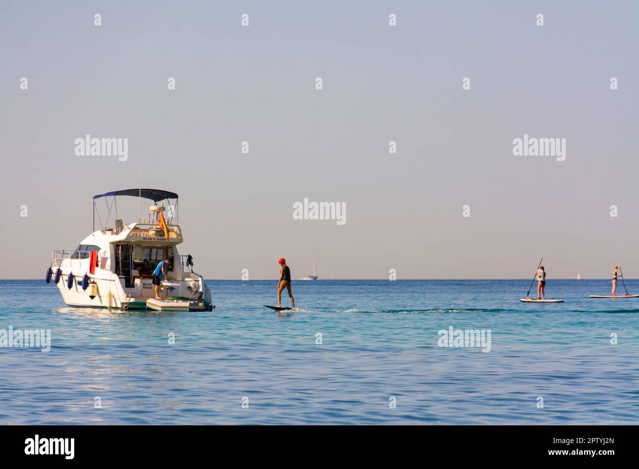 Palma, Mallorca, Spain. July 23, 2022 - Cala Major beach. Moored yacht and people with paddle surfing and fliteboard or jetsurf Stock Photo