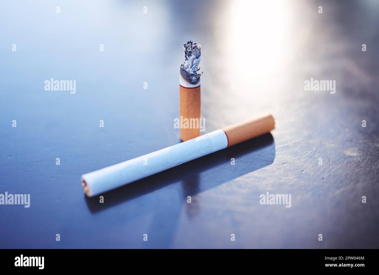 Smoking, tobacco and burning cigarette on table, close up of two cigarettes. Awareness for
