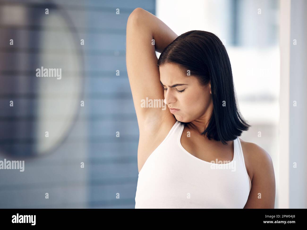 Woman smelling her armpit in a bathroom at her home before a shower for