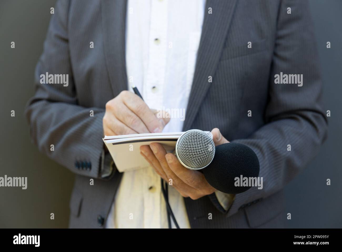 Journalist at news conference or media event, writing notes, holding ...