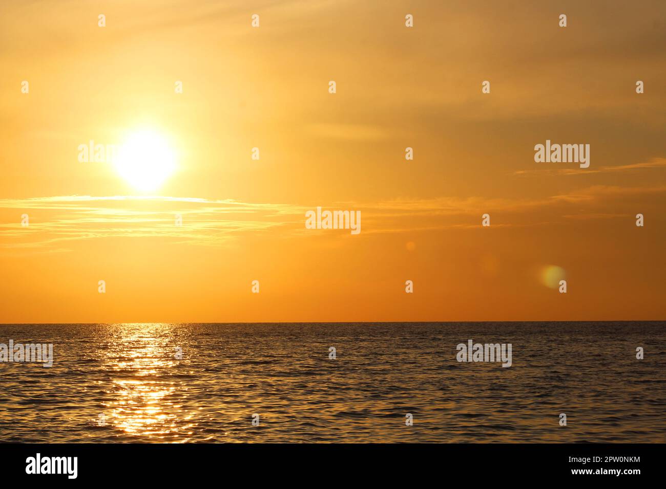 Beautiful sunset landscape at Mediterranean sea and orange sky above it with awesome sun golden reflection on calm waves. Stock Photo