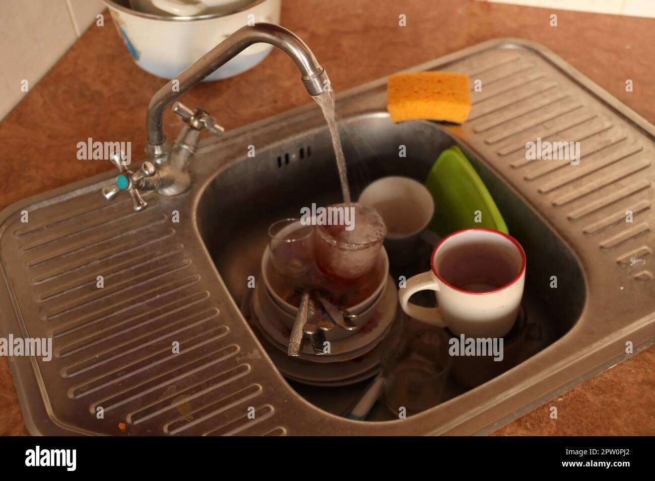 Stack of dirty dishes with food leftovers in the kitchen sink. Unwashed