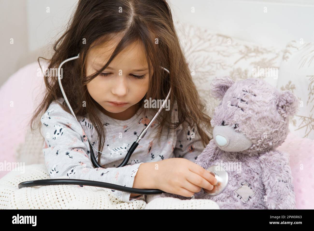 Serious, concentrated, careful small child, girl checking teddy bear