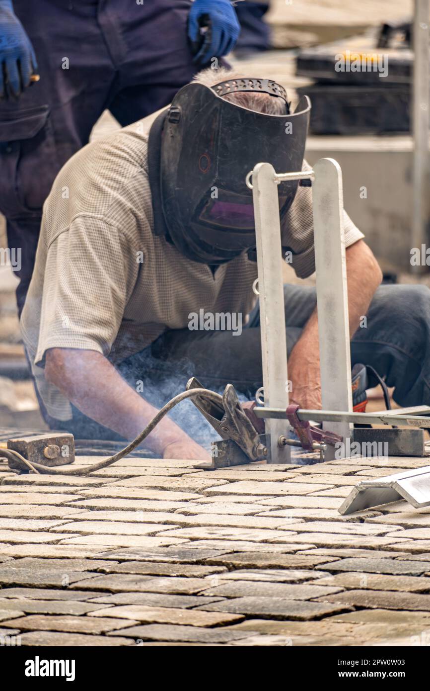 Welder maintenance worker with a welding mask at a construction site in the streets of Barcelona in construction works and urban improvement of munici Stock Photo