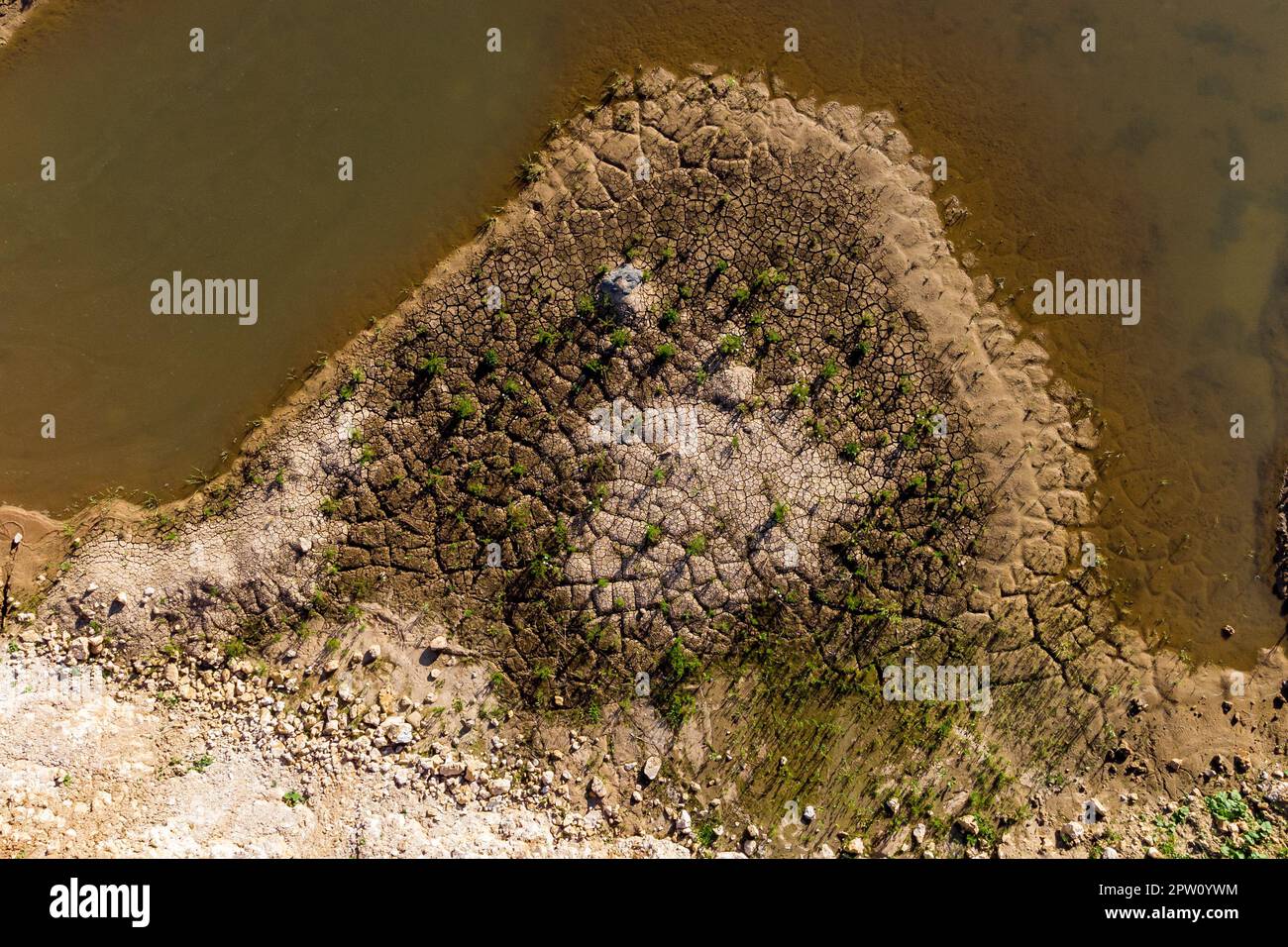The shore of a reservoir with silt is cracked from drying out. Drying