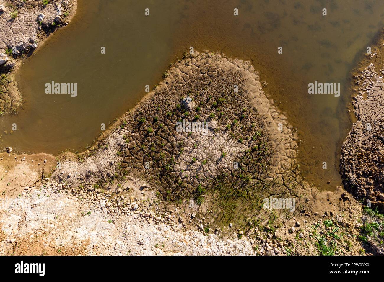 The shore of a reservoir with silt is cracked from drying out. Drying