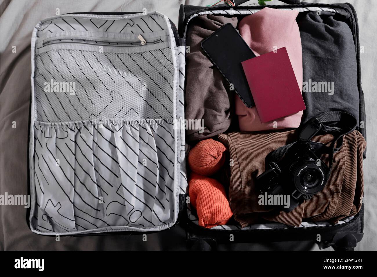 top view of small suitcase with digital camera and passport on the bed Stock Photo