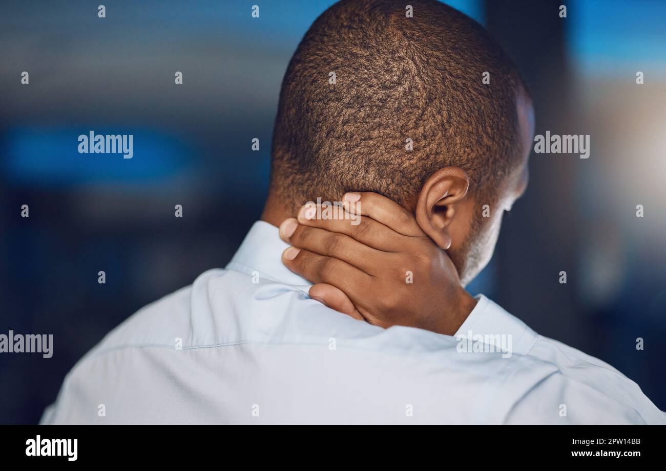 Above rearview young african man holding his neck in pain. African american business man suffering from the stress and pressure of deadlines which is Stock Photo
