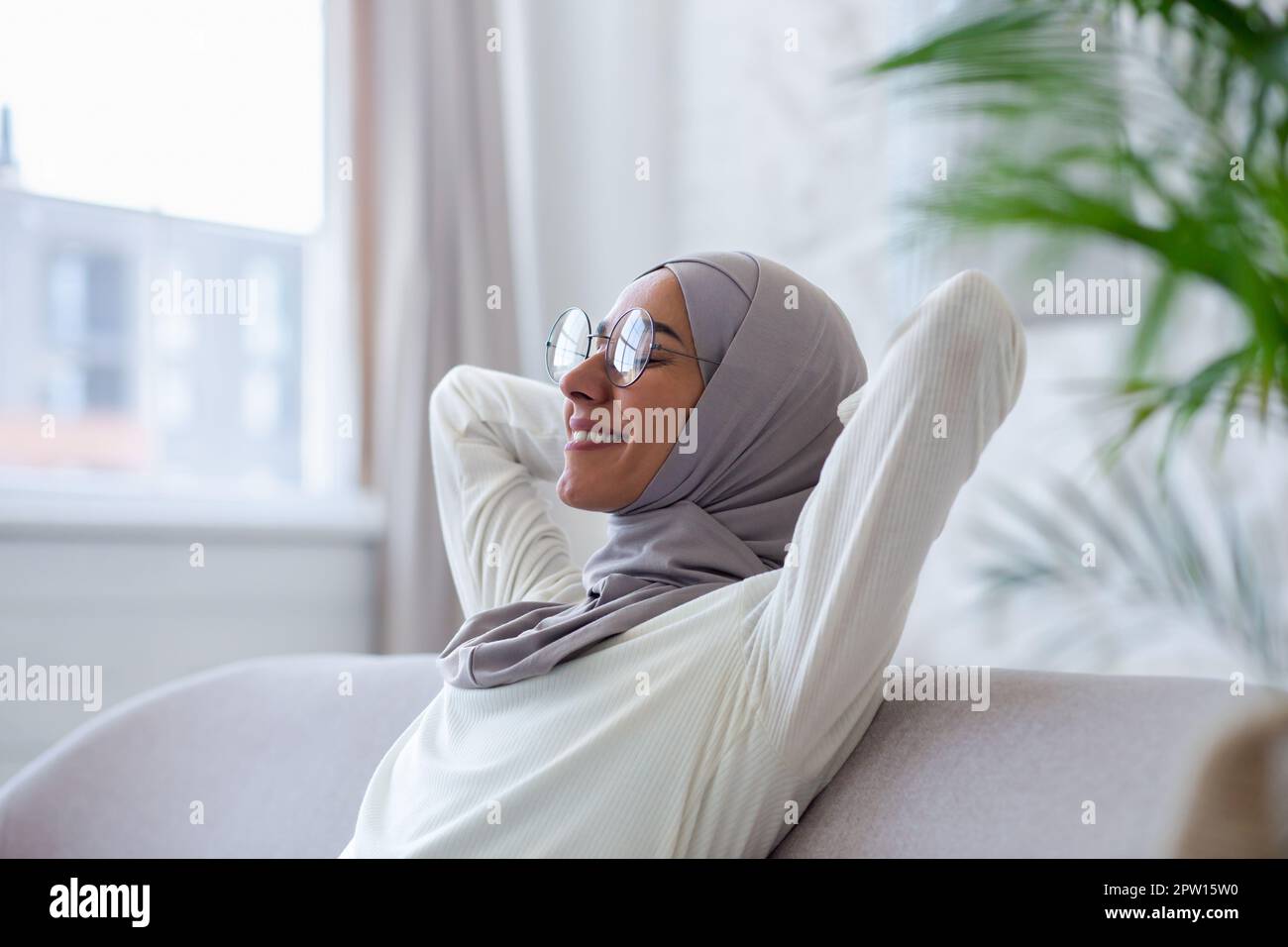 Close-up photo. Smiling Muslim young woman in hijab and glasses sitting ...