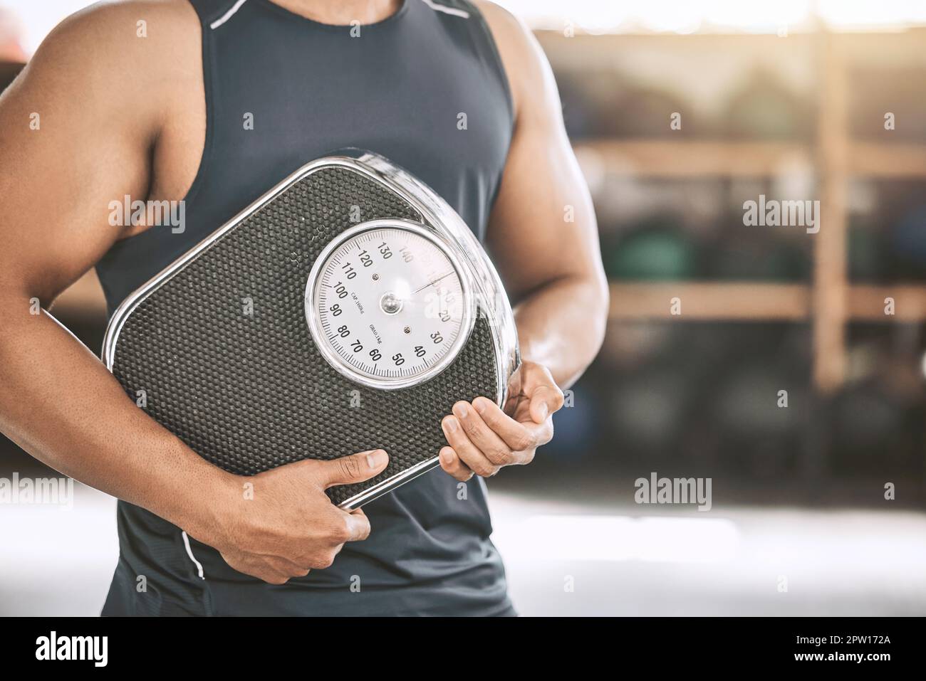 Hand of a fit man holding a scale. Strong man measuring his weight at