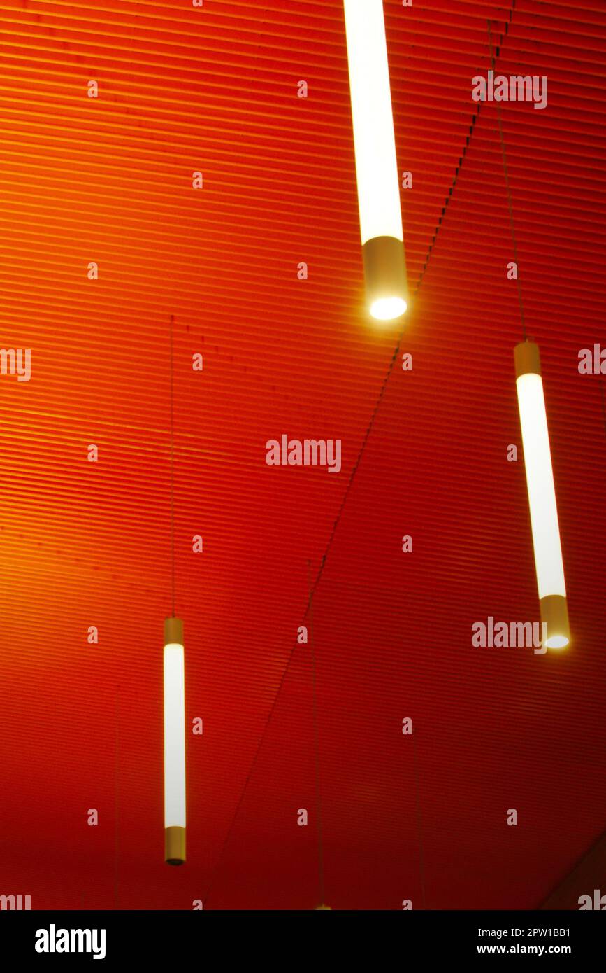 Intense orange ceiling with vertical light tubes. Modern architecture, interior. Stock Photo