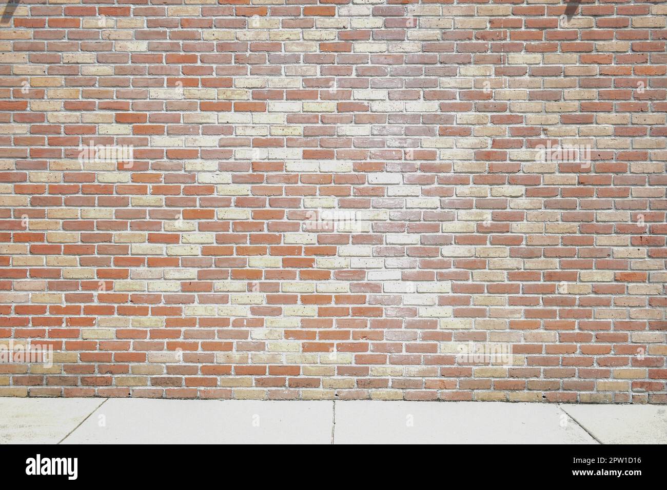 Muted tones brick wall and white sidewalk Stock Photo
