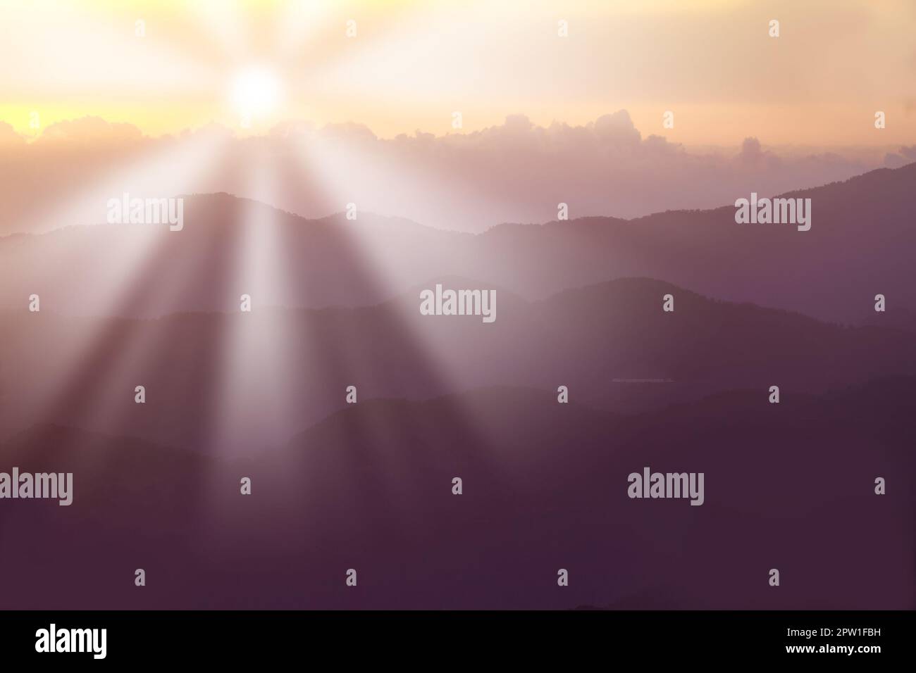 Sun rising behind mountains in summer. Sun rays causing lensflare over