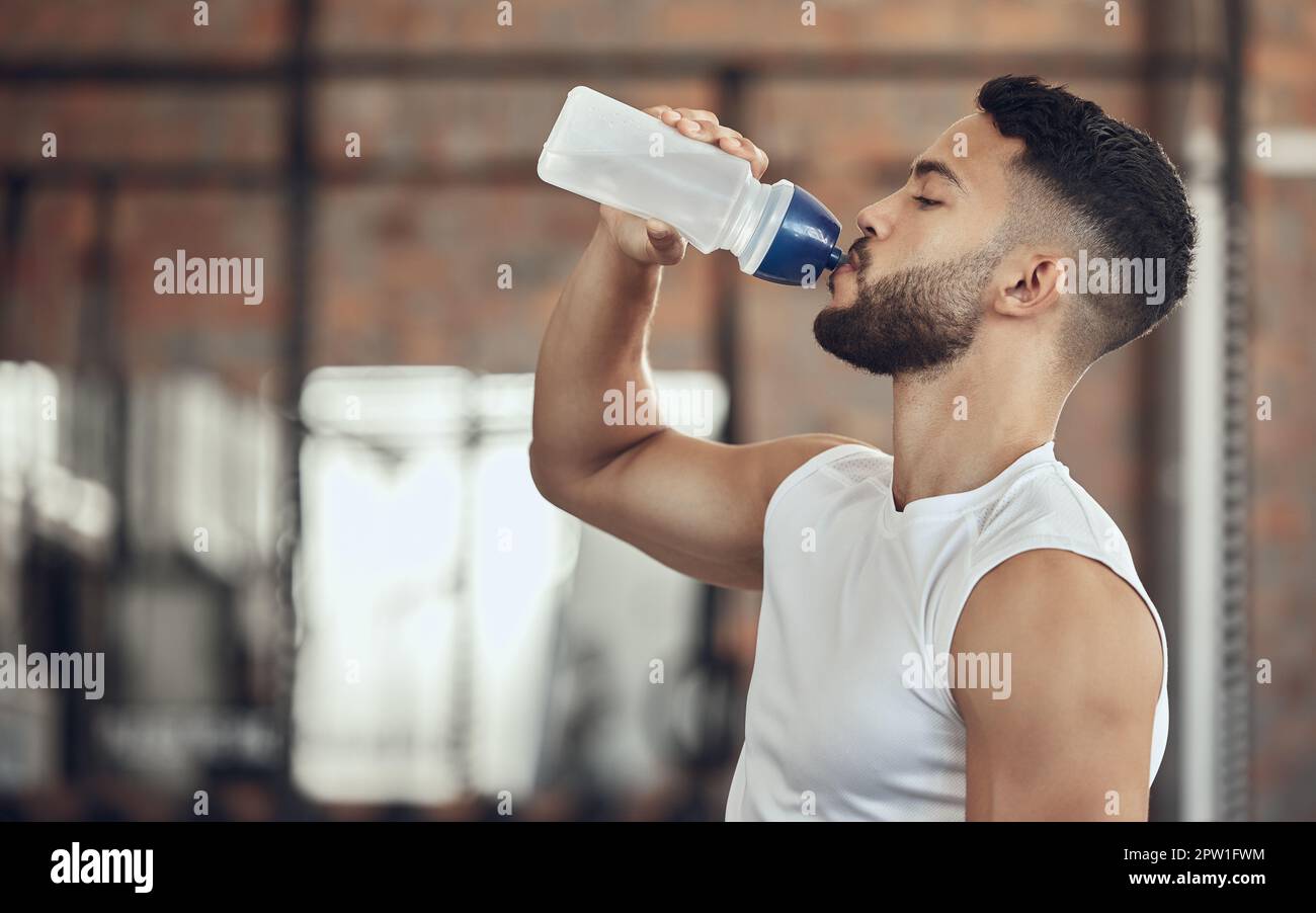 Man taking a break from exercise to hydrate.Young man drinking water