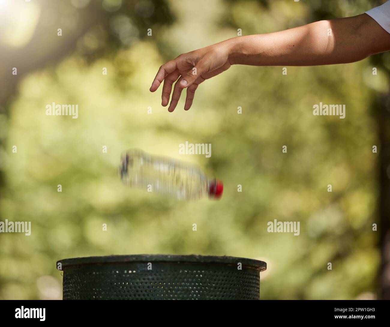 One unknown mixed race woman throwing a plastic bottle in a bin to