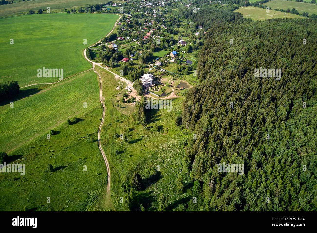 Aerial view of a small village surrounded by green fields and forests ...