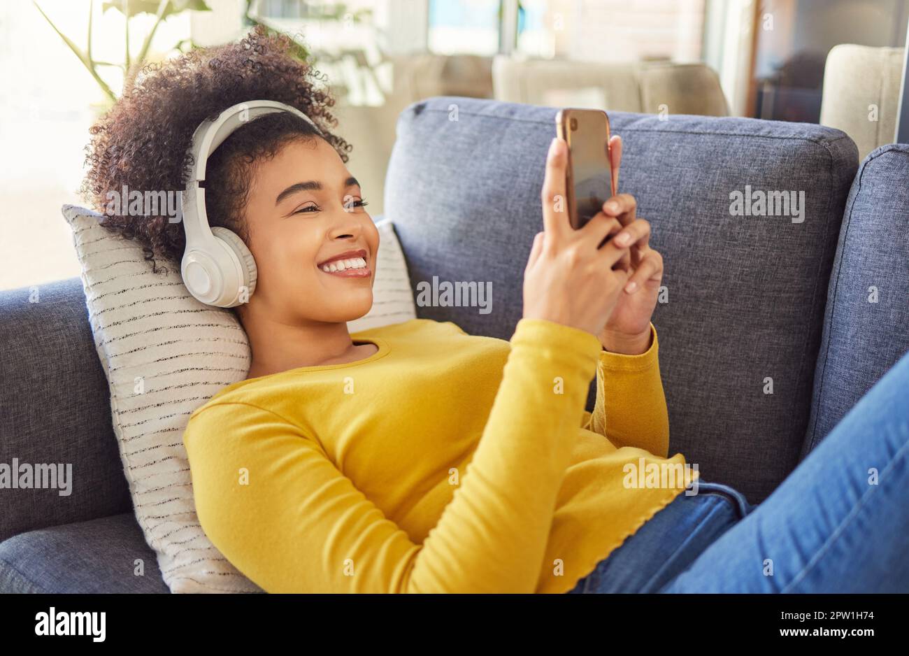 Young joyful mixed race woman wearing headphones and listening to music ...