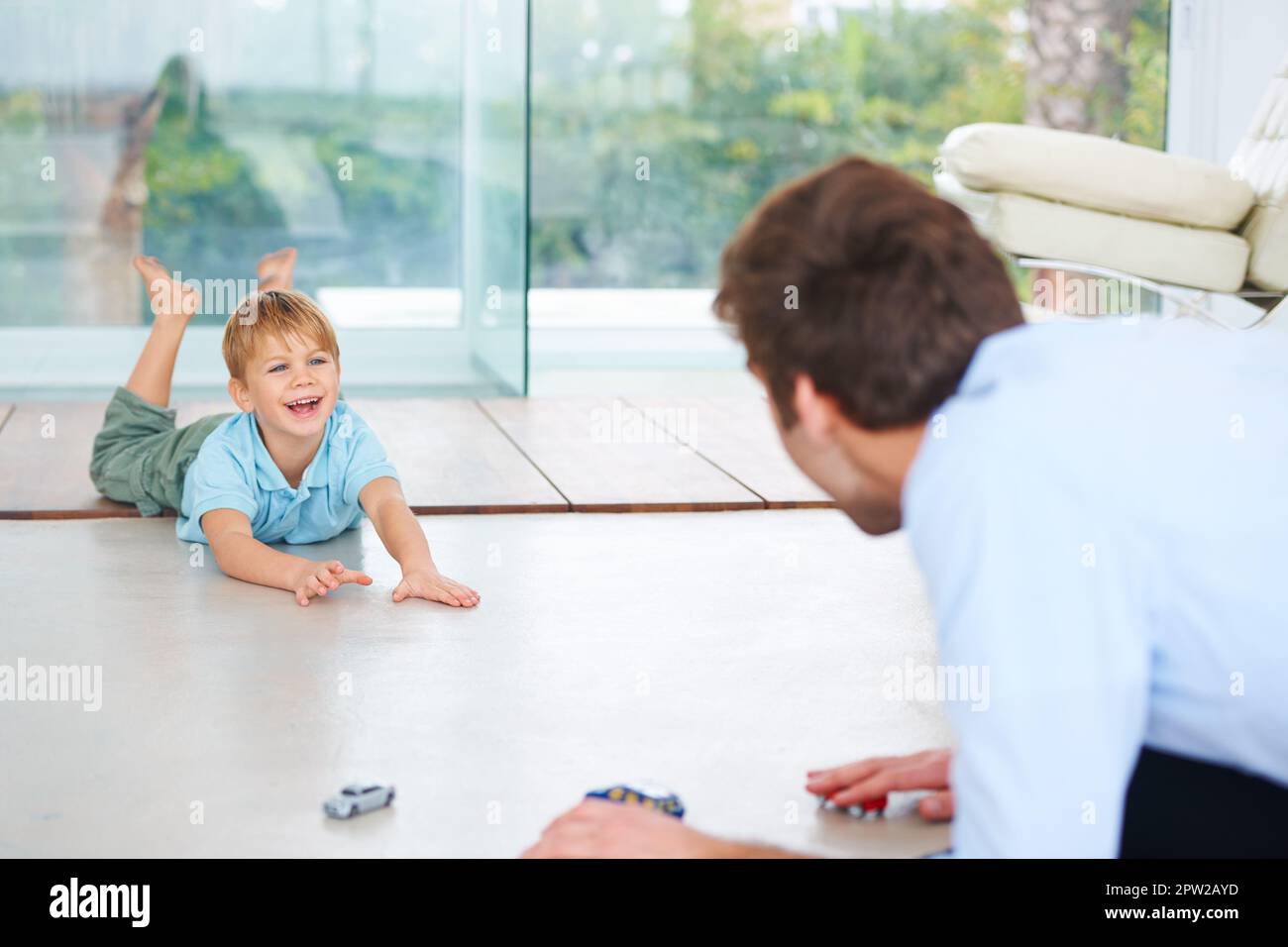 So glad Dads home. A little boy playing with his father on the floor Stock Photo