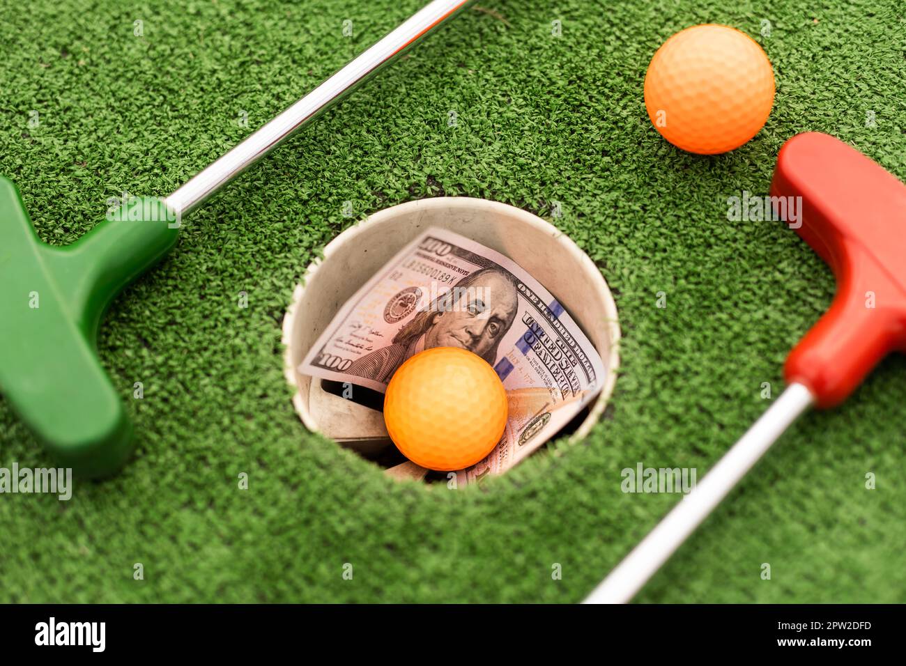 Mini Golf club, ball and money on the artificial grass Stock Photo