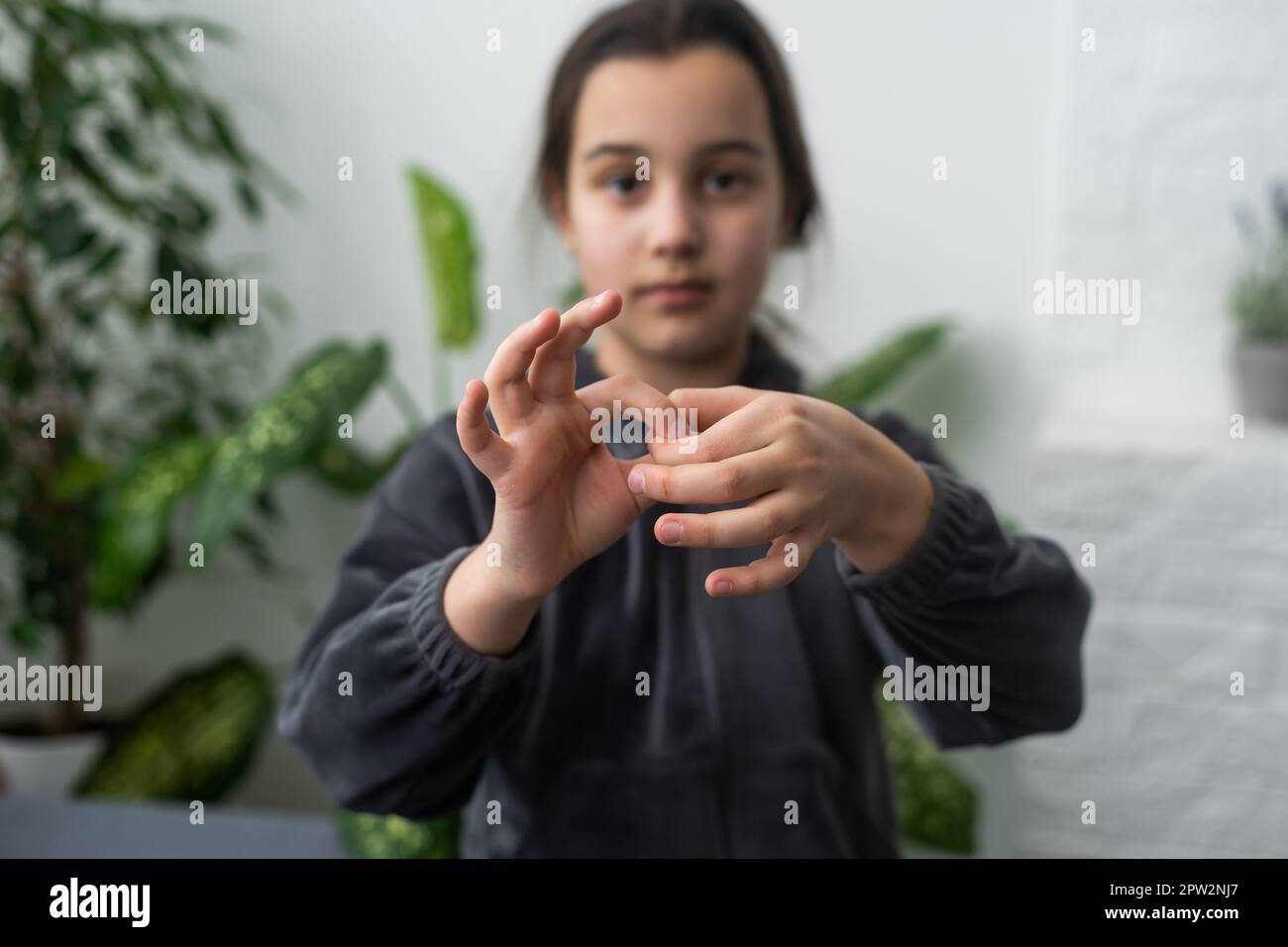 Cute deaf mute girl using sign language on light background Stock Photo