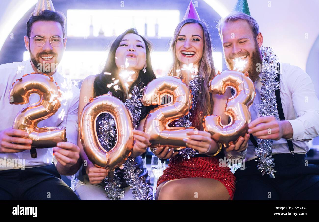 Men and women celebrating the new year 2023 with sparklers and wine Stock Photo