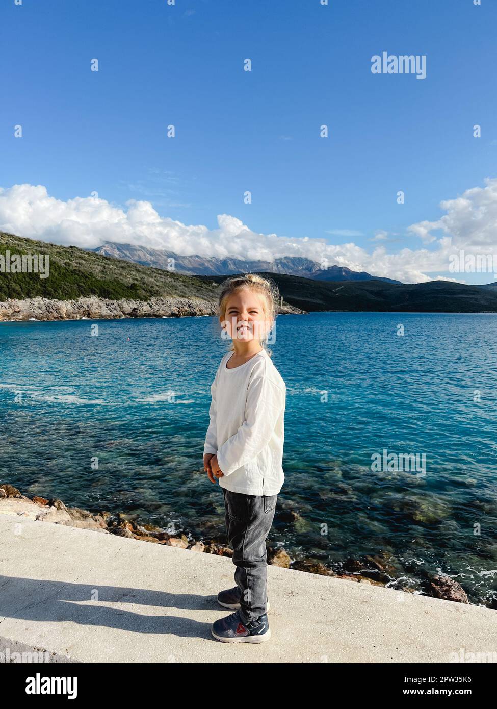 Little smiling girl stands on the pier by the sea Stock Photo - Alamy