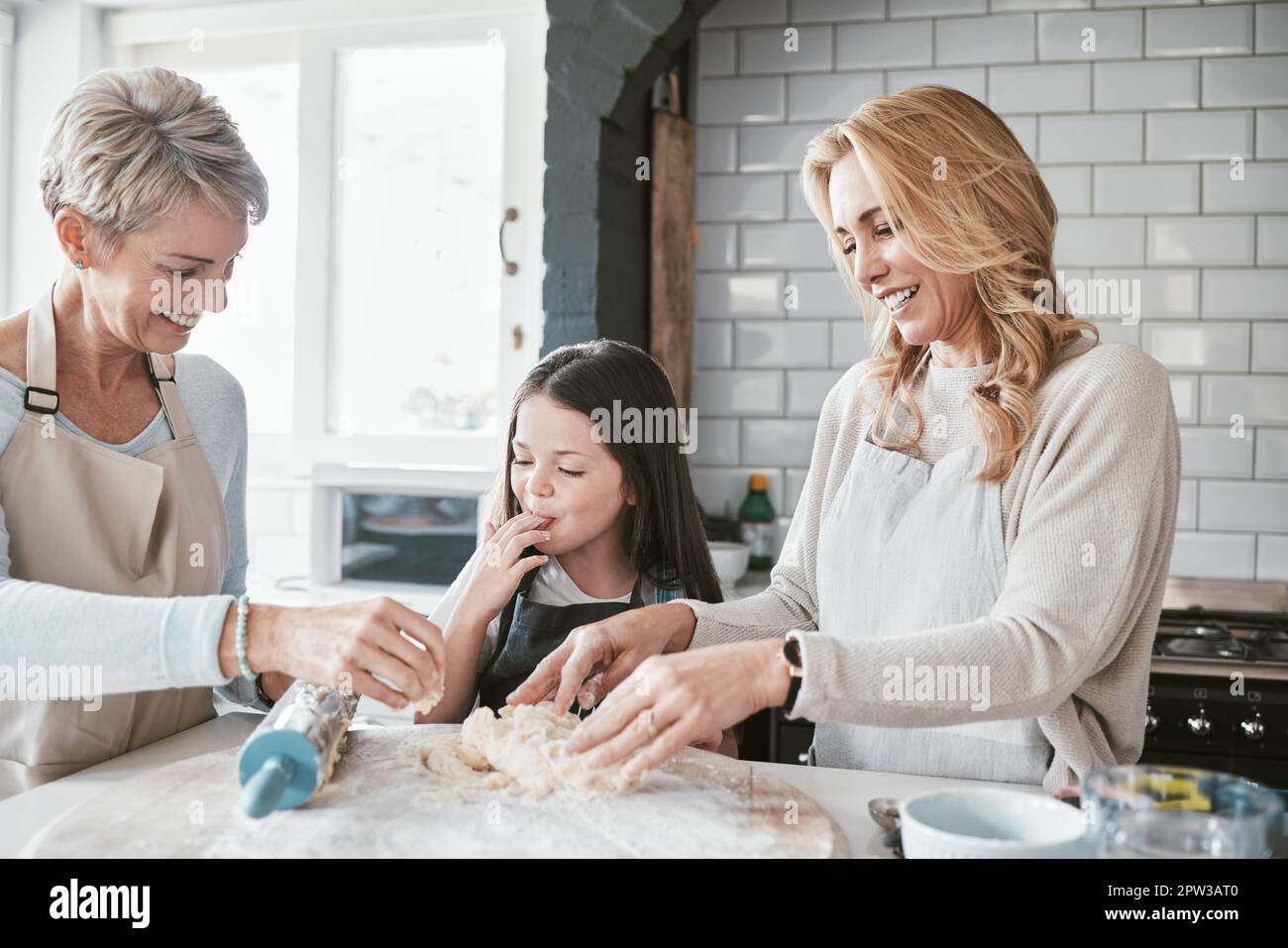 Mom, grandmother and kid baking with flour dough at kitchen counter