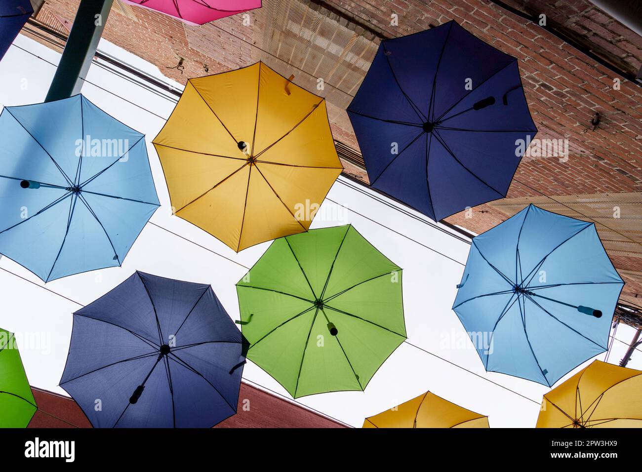 Looking up at colorful umbrellas and red brick walls in downtown