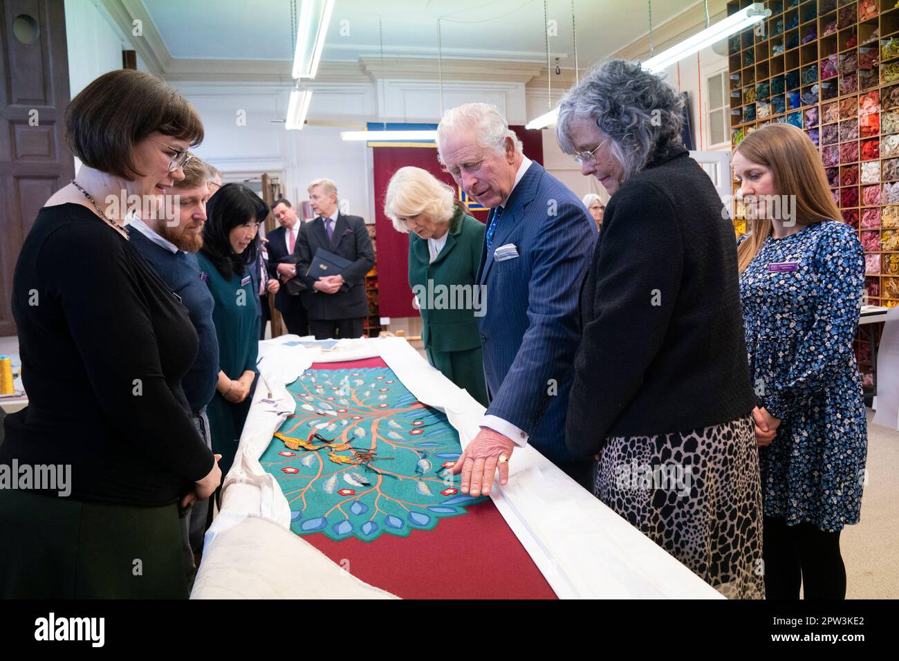 King Charles III and the Queen Consort look at the needlework on part