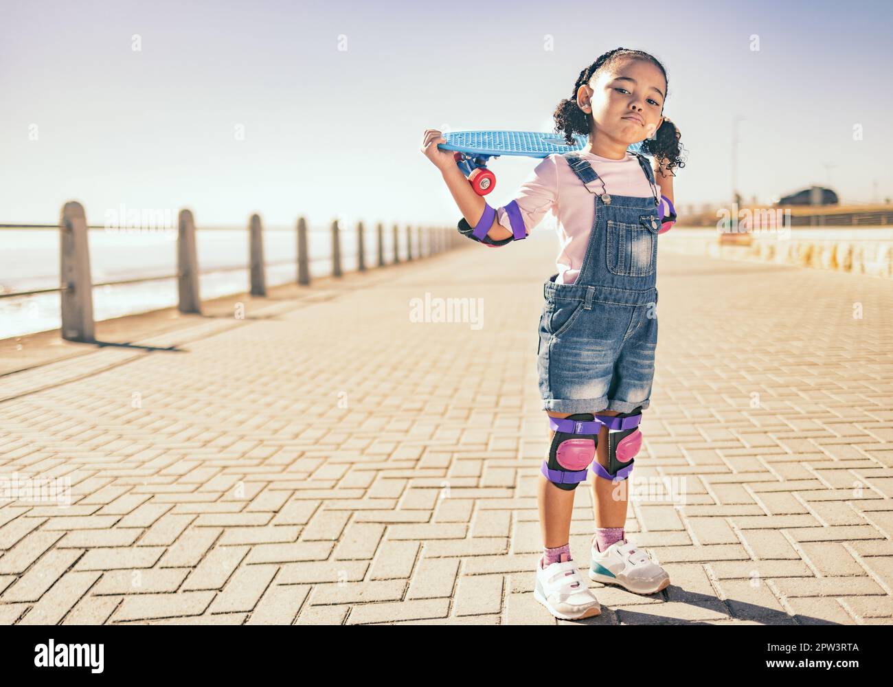 Young girl, skateboard and ocean walk of a child holding a board to
