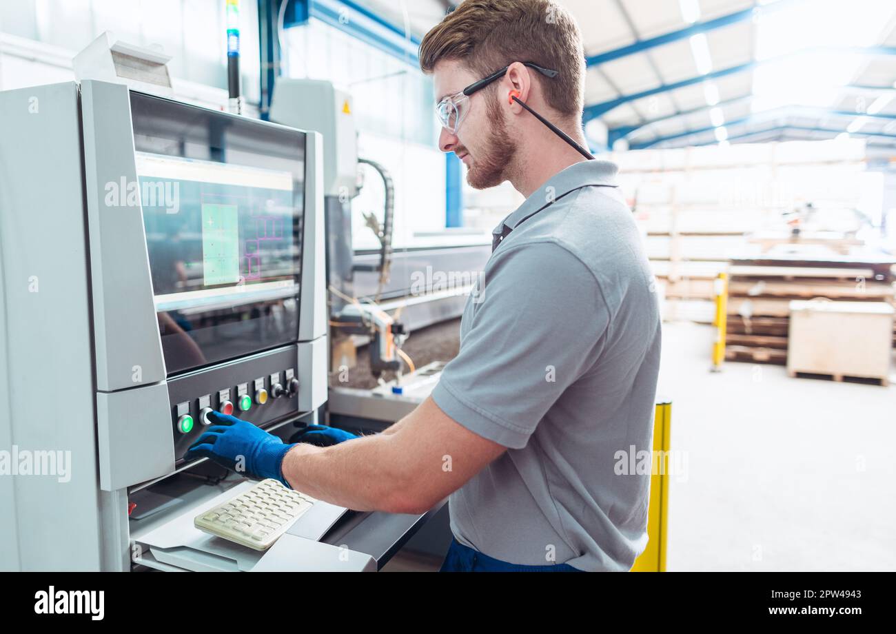Worker operating a water jet cutting machine by pressing buttons and
