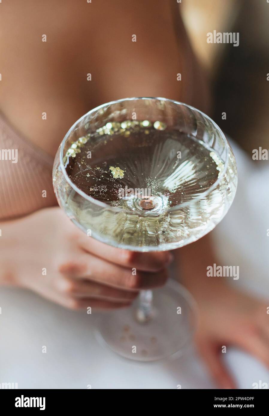 From above soft focus of anonymous woman with glass goblet of fizzing champagne enjoying banquet Stock Photo