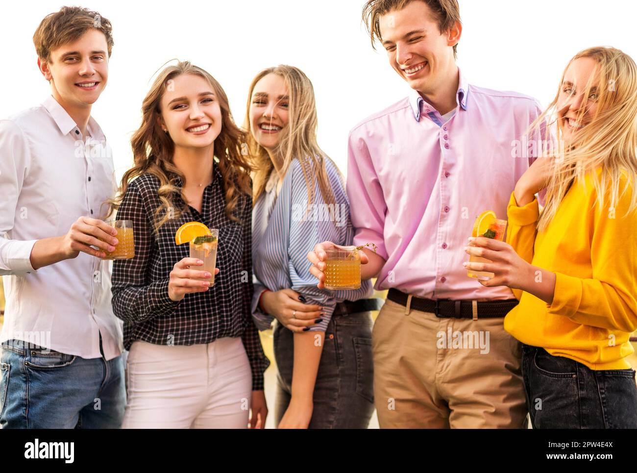 Happy men and women clinking glasses of fruit cocktails and proposing toast during the party Stock Photo