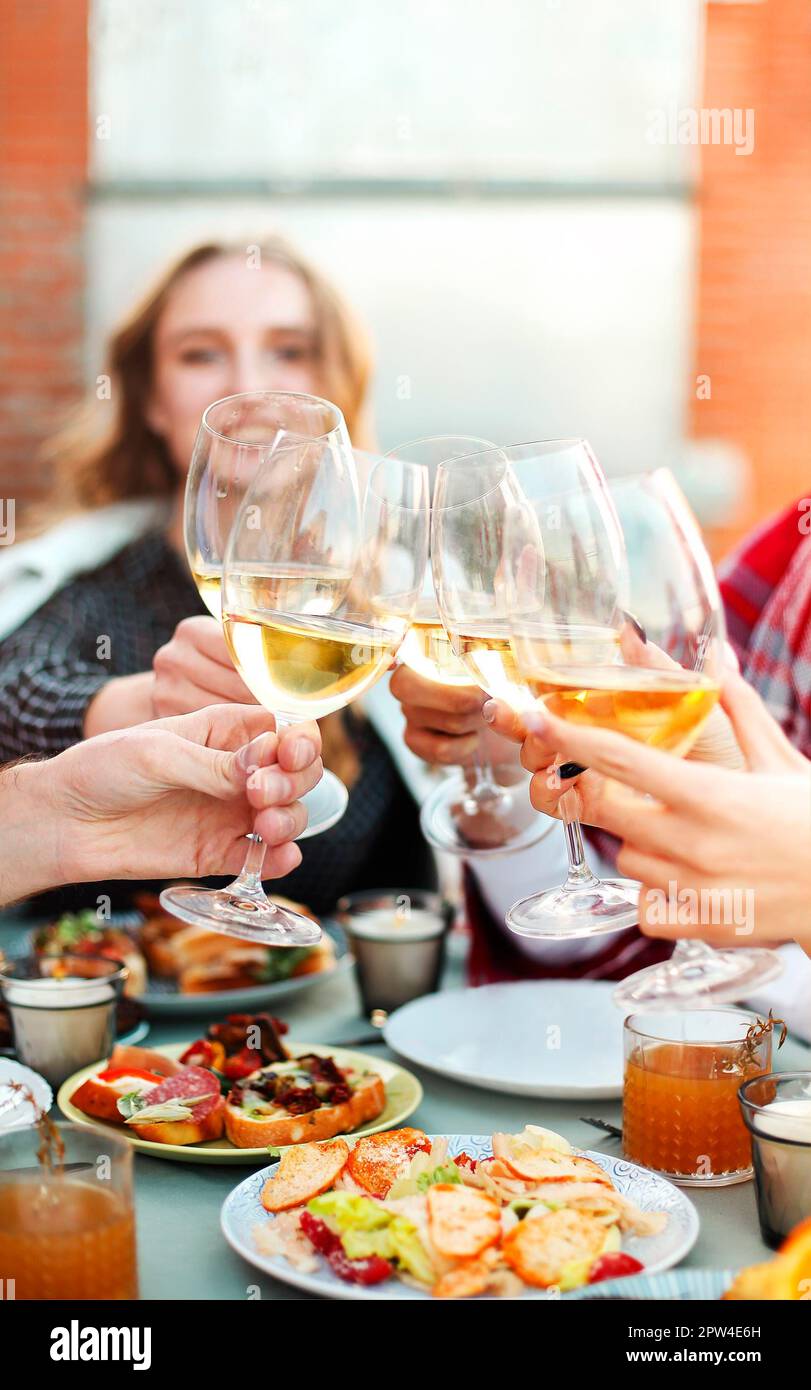 Group of anonymous people clinking wineglasses and proposing toast during party on rooftop Stock Photo
