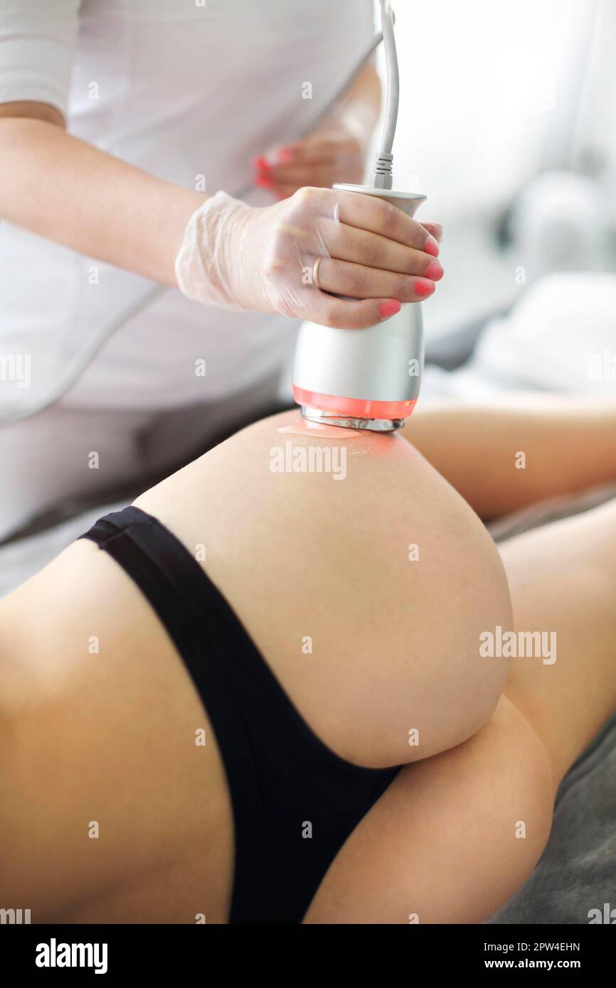 Ultrasound body shaping treatment. Female client getting anti-cellulite and anti-fat treatment on her tight buttocks at beauty salon from qualified Stock Photo
