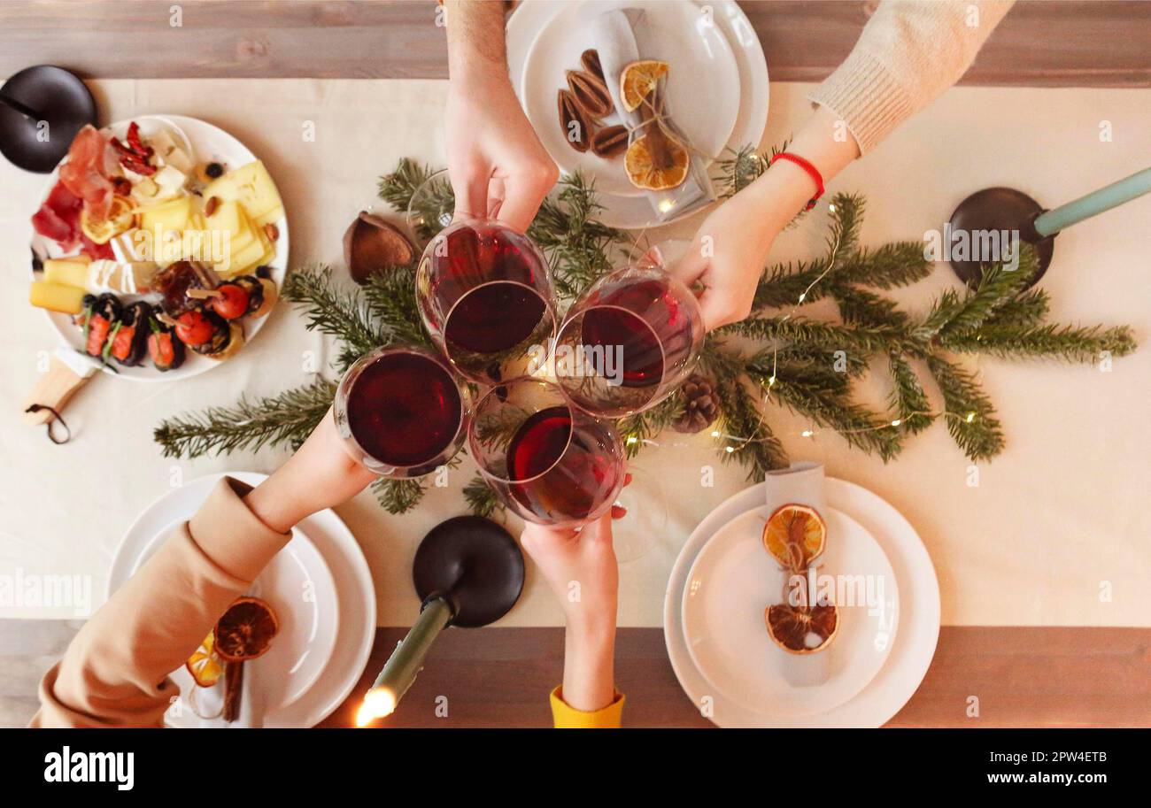 Top view of anonymous friends clinking glasses of wine over table decorated for Christmas celebration at home Stock Photo