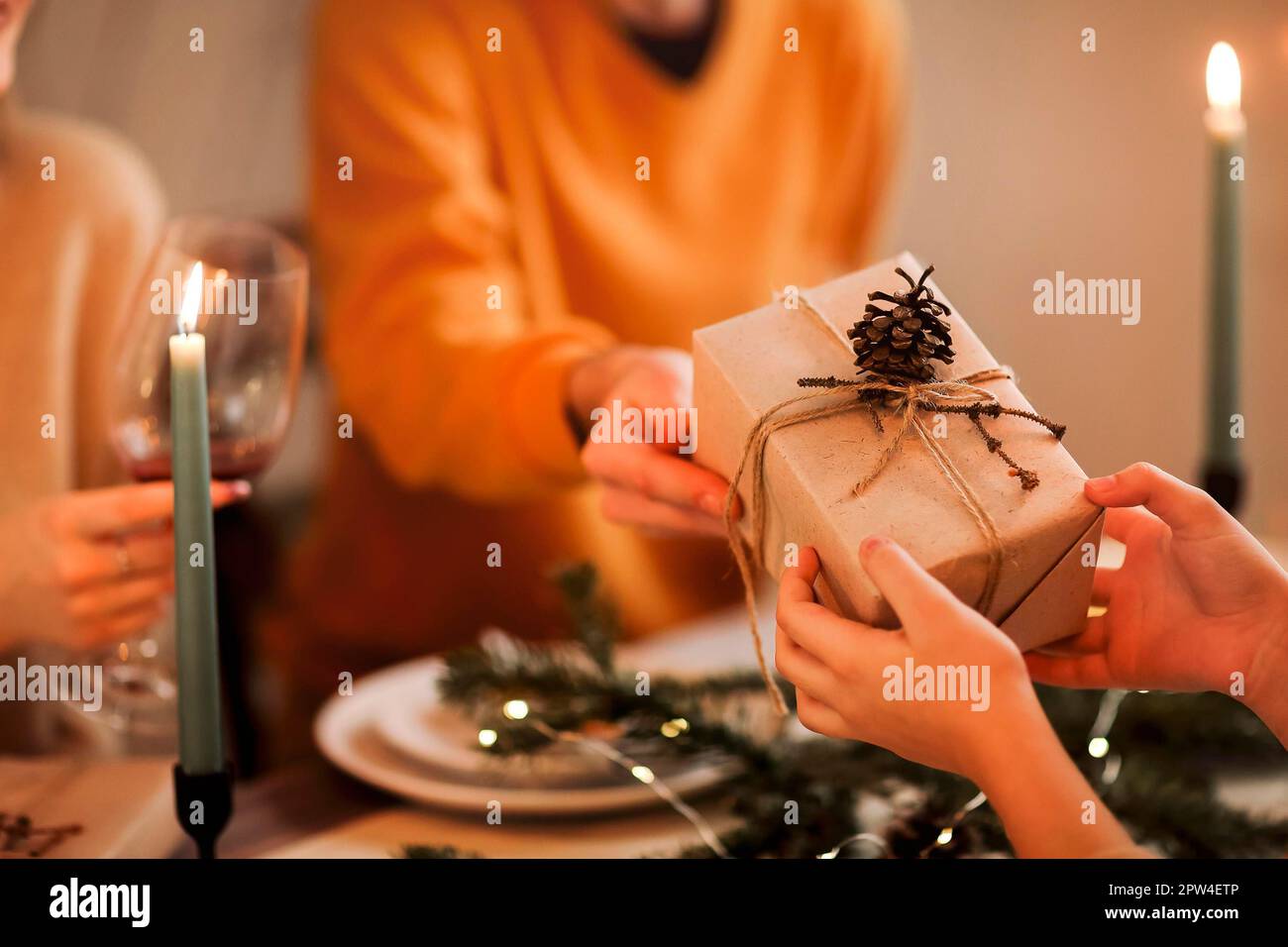 Soft focus of unrecognizable person giving wrapped gift to friend while sitting at table and celebrating Christmas together Stock Photo