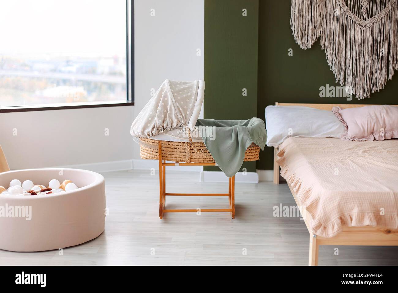 Photo of bedroom freshly renovated for newborn, tastefully decorated in minimalist style with boho elements as macrame decoration on wall, baby crib Stock Photo