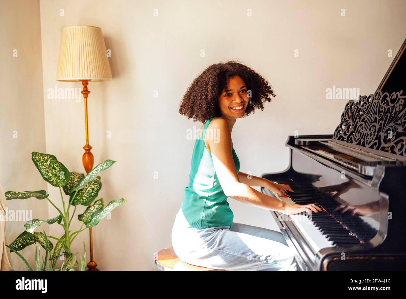 Young black lady playing a piano. Happy smiling woman enjoy fun learning to  play piano music instrument Stock Photo - Alamy
