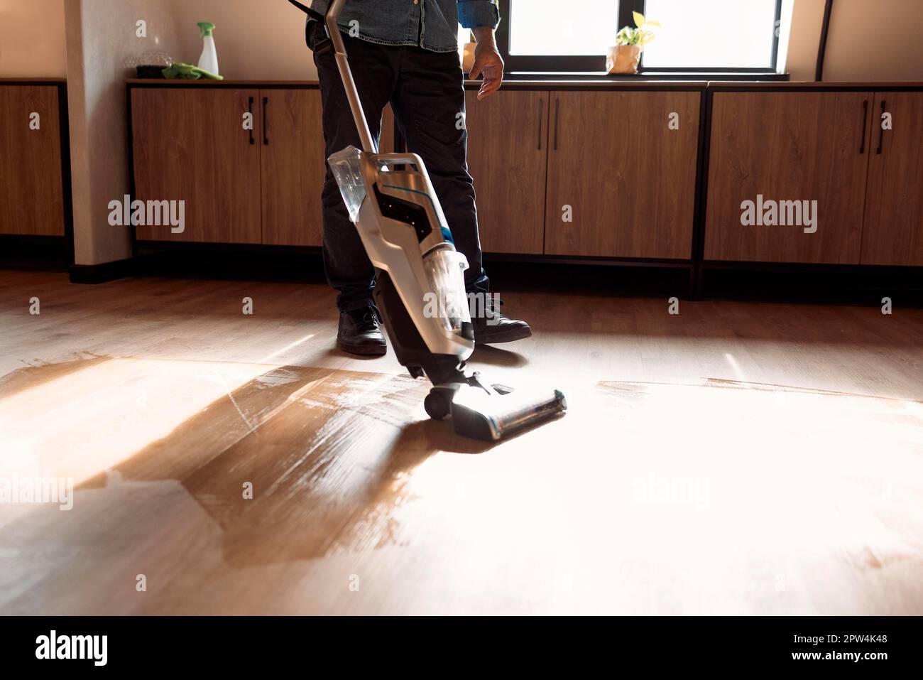 man vacuuming wooden floor in loft iving room with vacuum