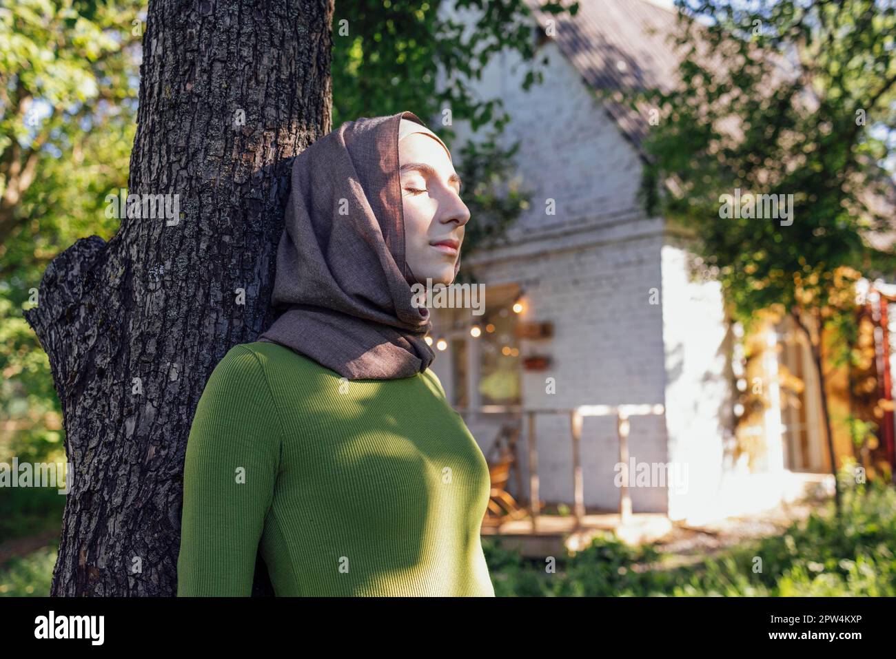 Muslim teen girl hugging a tree. Close up portrait of a young female in a hijab and casual clothes in the park. Protecting the environment and caring Stock Photo