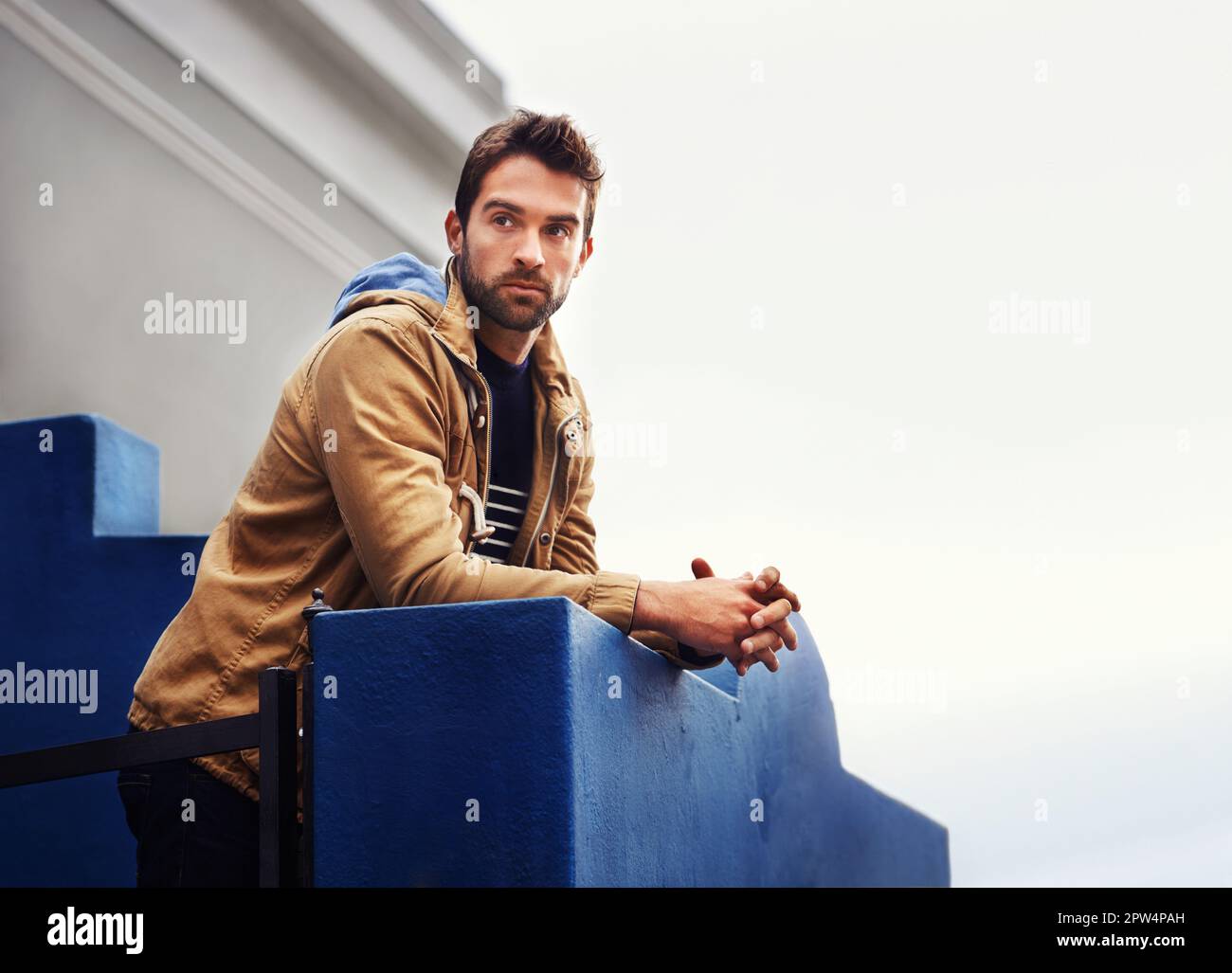 Whatever you do today, do it looking good. a stylish young man leaning over a balcony Stock Photo