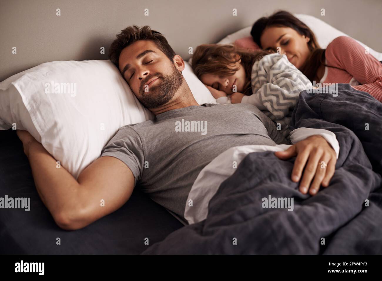 Snug between mom and dad. a little girl sleeping beside her parents in